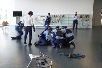 犯人役が複数の警察官に取り押さえられる様子