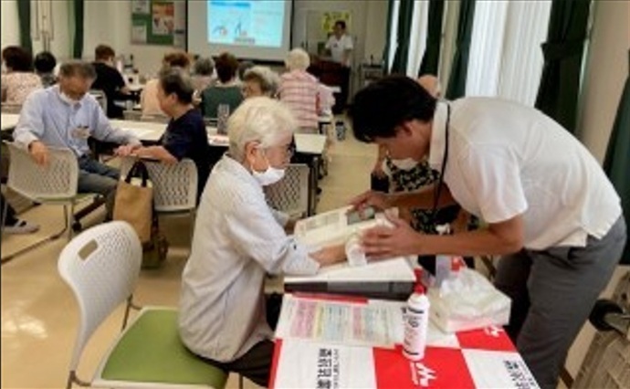 職員が女性の骨強度を測定している写真